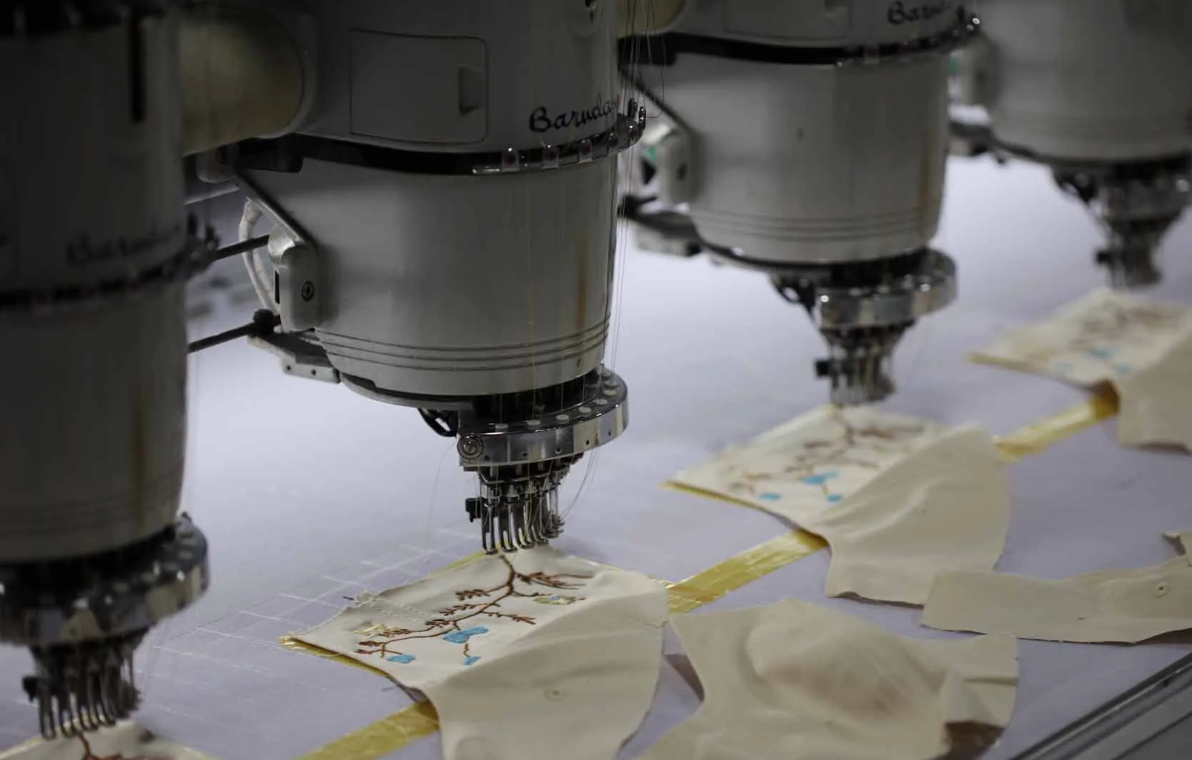 Multi-head embroidery machines producing decorated cap panels
