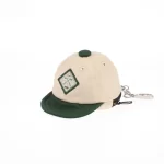 Beige and dark-green mini cap bag keychain with golf patch, front angle